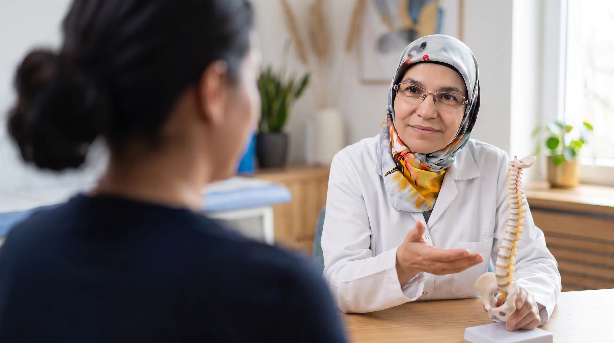 Uzm. Dr. Emine Yüksel Kars hastasıyla omurga modeli üzerinden tedavi planını konuşuyor — Ankara fizik tedavi